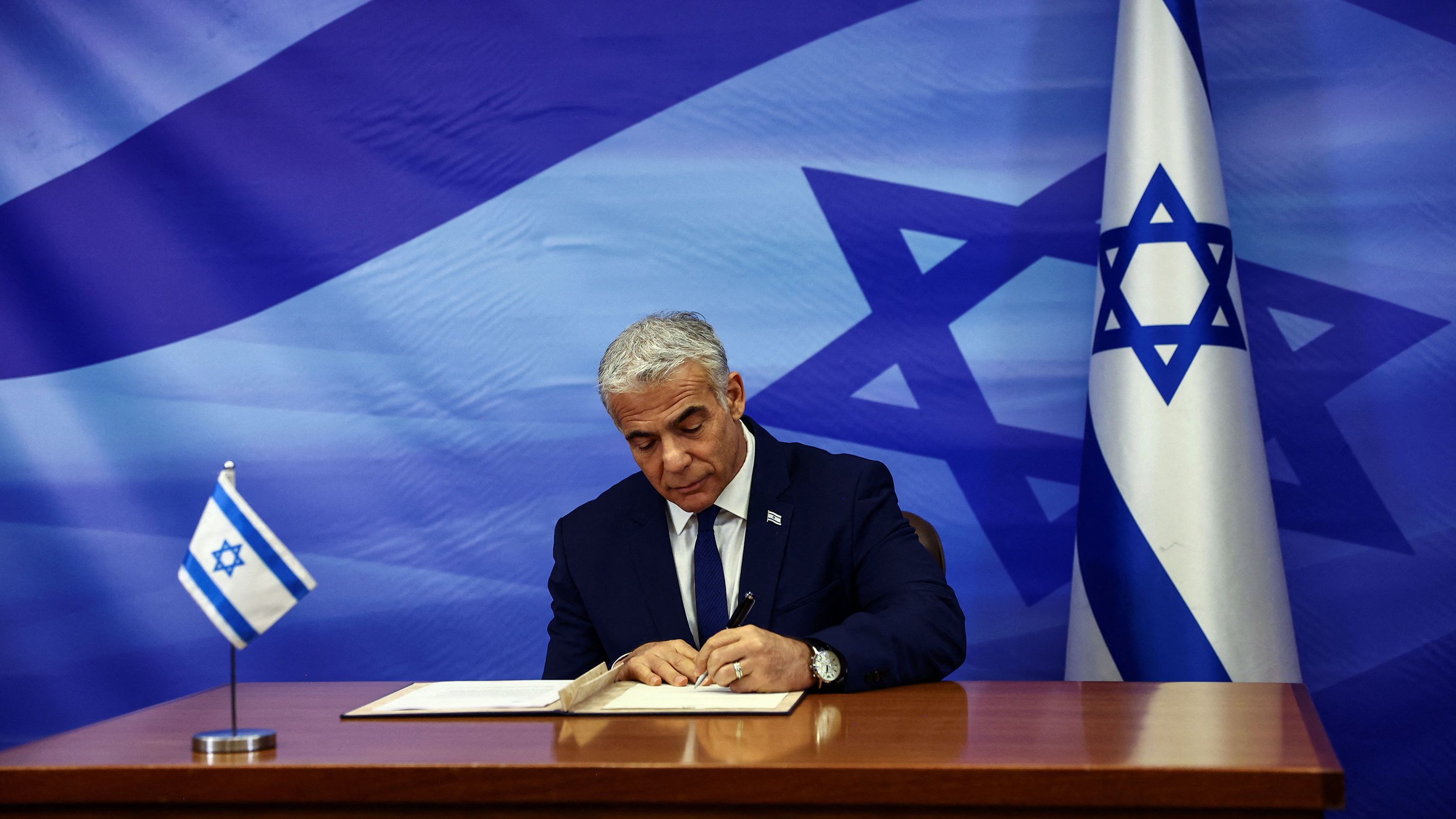 Israeli leader Yair Lapid signs the deal setting a maritime border between Israel and Lebanon, at the prime minister's office in Jerusalem on October 27.