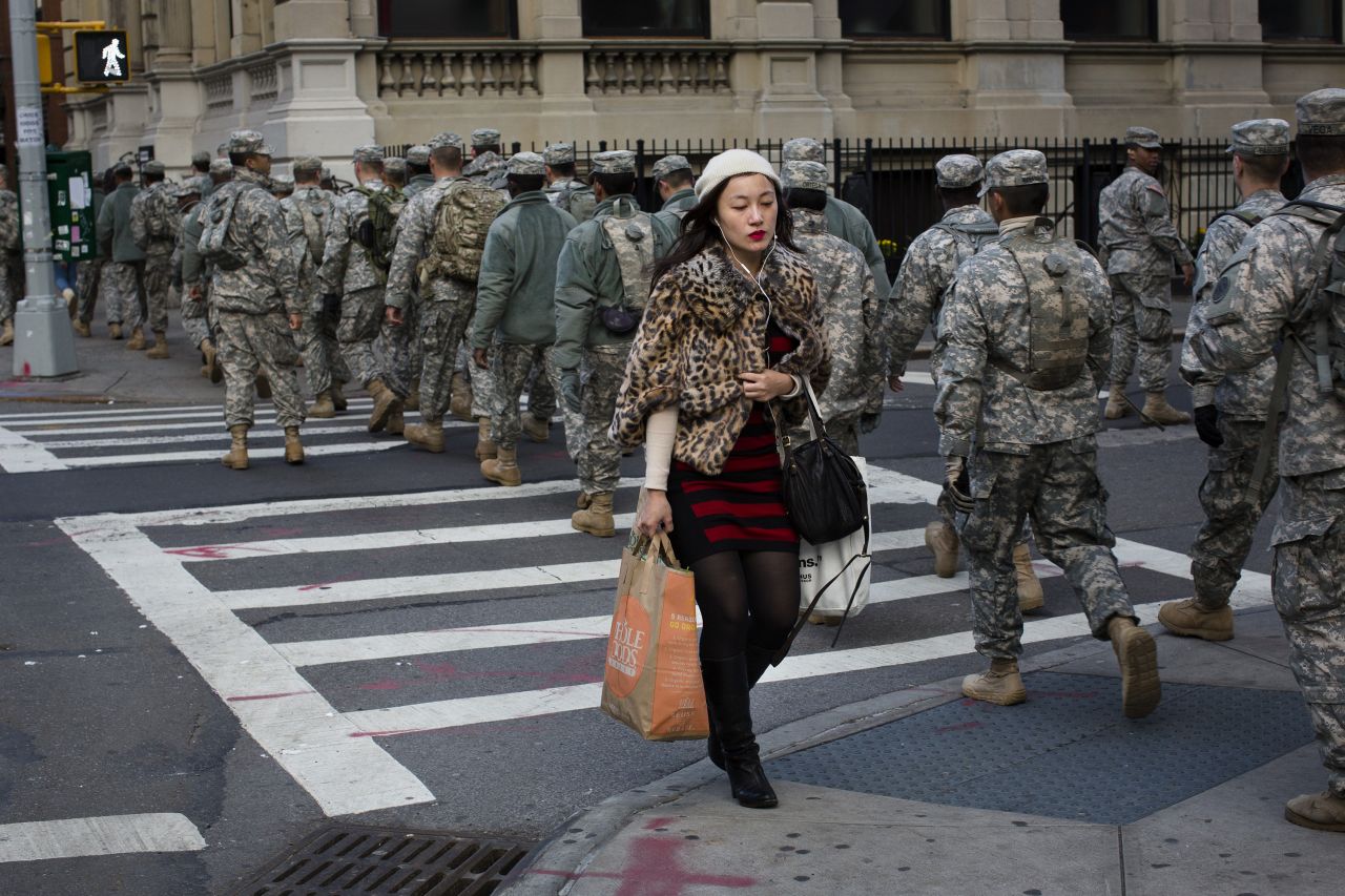 A woman carrying groceries passes a group of National Guardsmen as they march down a street in Manhattan on November 3, 2012.