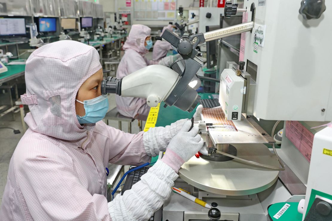 A woman inspects the quality of a chip at a manufacturer of IC encapsulation in Nantong in east China's Jiangsu province Friday, Sept. 16, 2022.