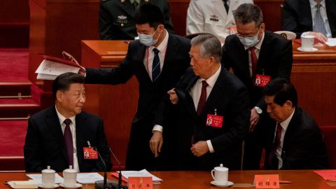 Former Chinese leader Hu Jintao is taken by the arm and escorted out.