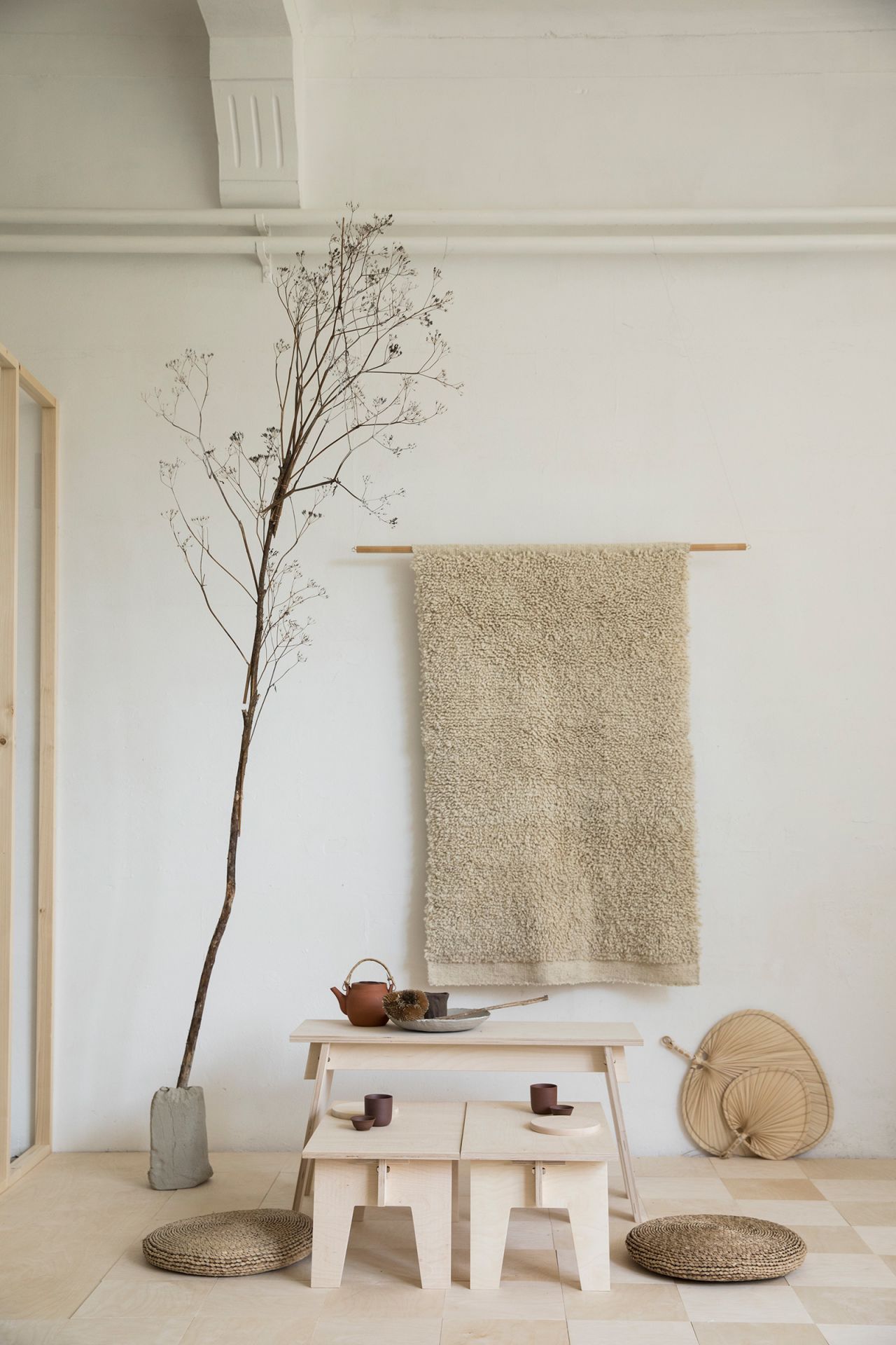 Low, soft white tables designed by Woodchuck pair with tan tones and an indoor tree, styled by Tinta.