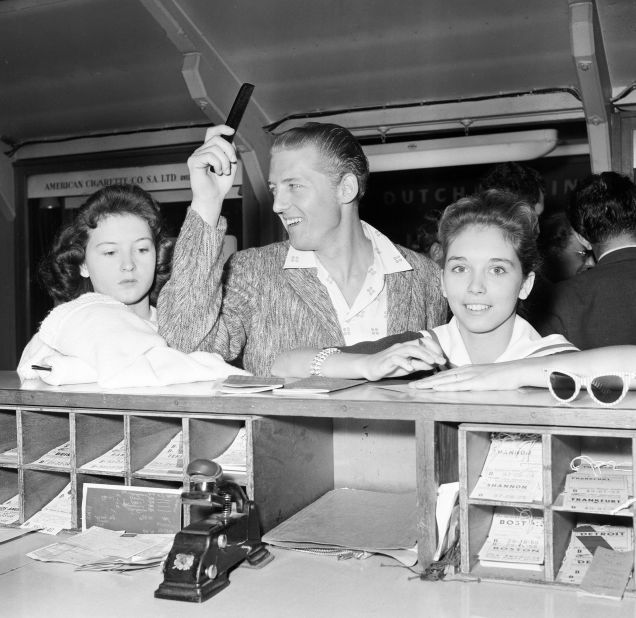 Lewis signs immigration cards with Myra, right, and his sister Jean as they leave London to come back to the United States in 1958.