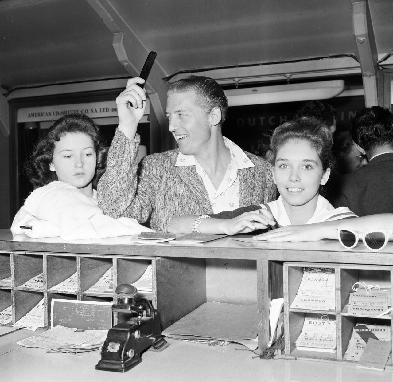 Lewis signs immigration cards with Myra, right, and his sister Jean as they leave London to come back to the United States in 1958.
