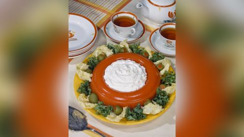 A Jell-O salad with whipped cream, garnished with olives.