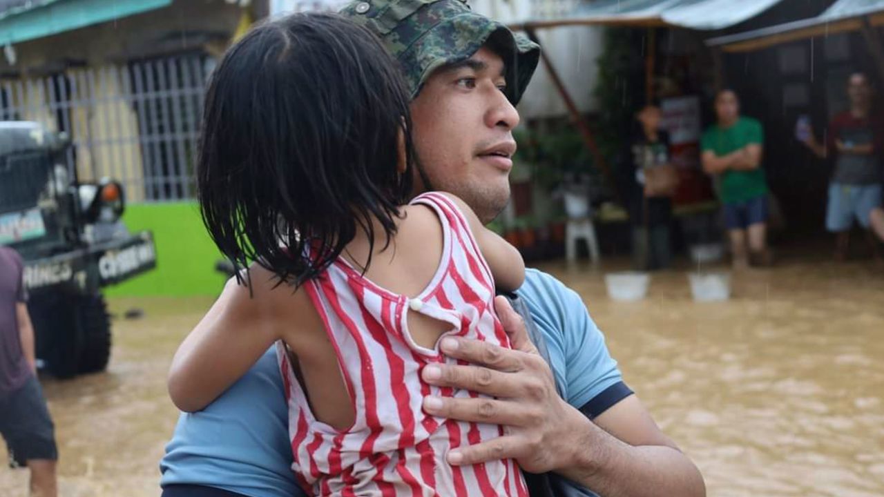 A rescuer carries a child to safer grounds amid flooding in the Philippines caused by Tropical Storm Nalgae. 