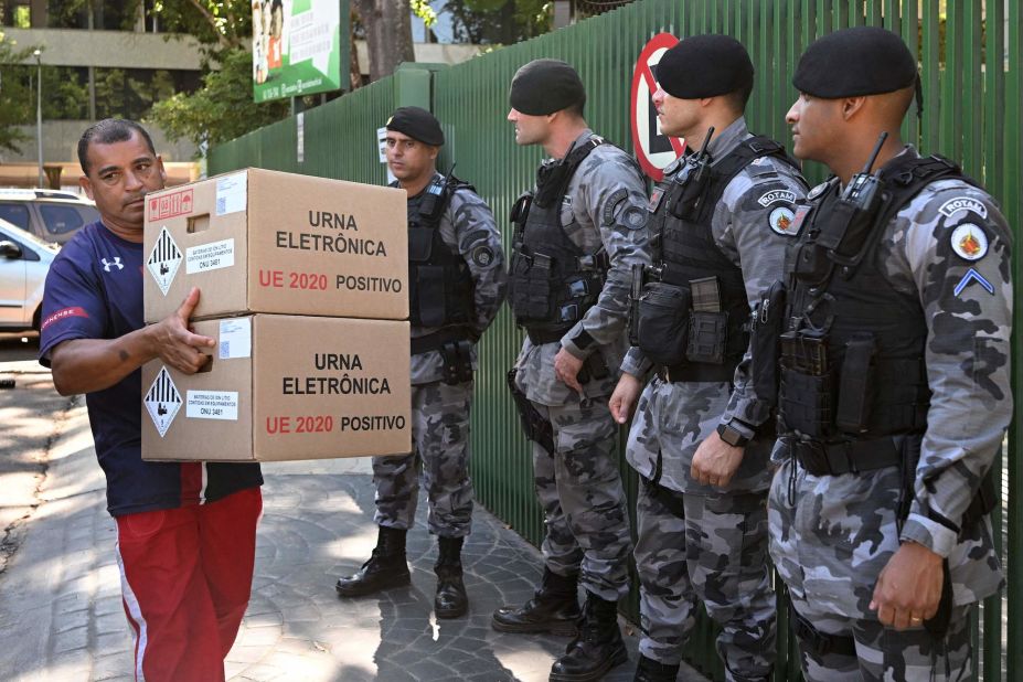 An Electoral Court employee carries electronic ballot boxes to a polling station guarded by police officers in Brasília on October 28.