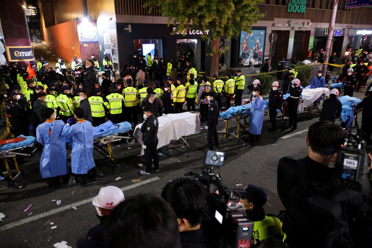 Rescue team members wait with stretchers to remove bodies from the scene.