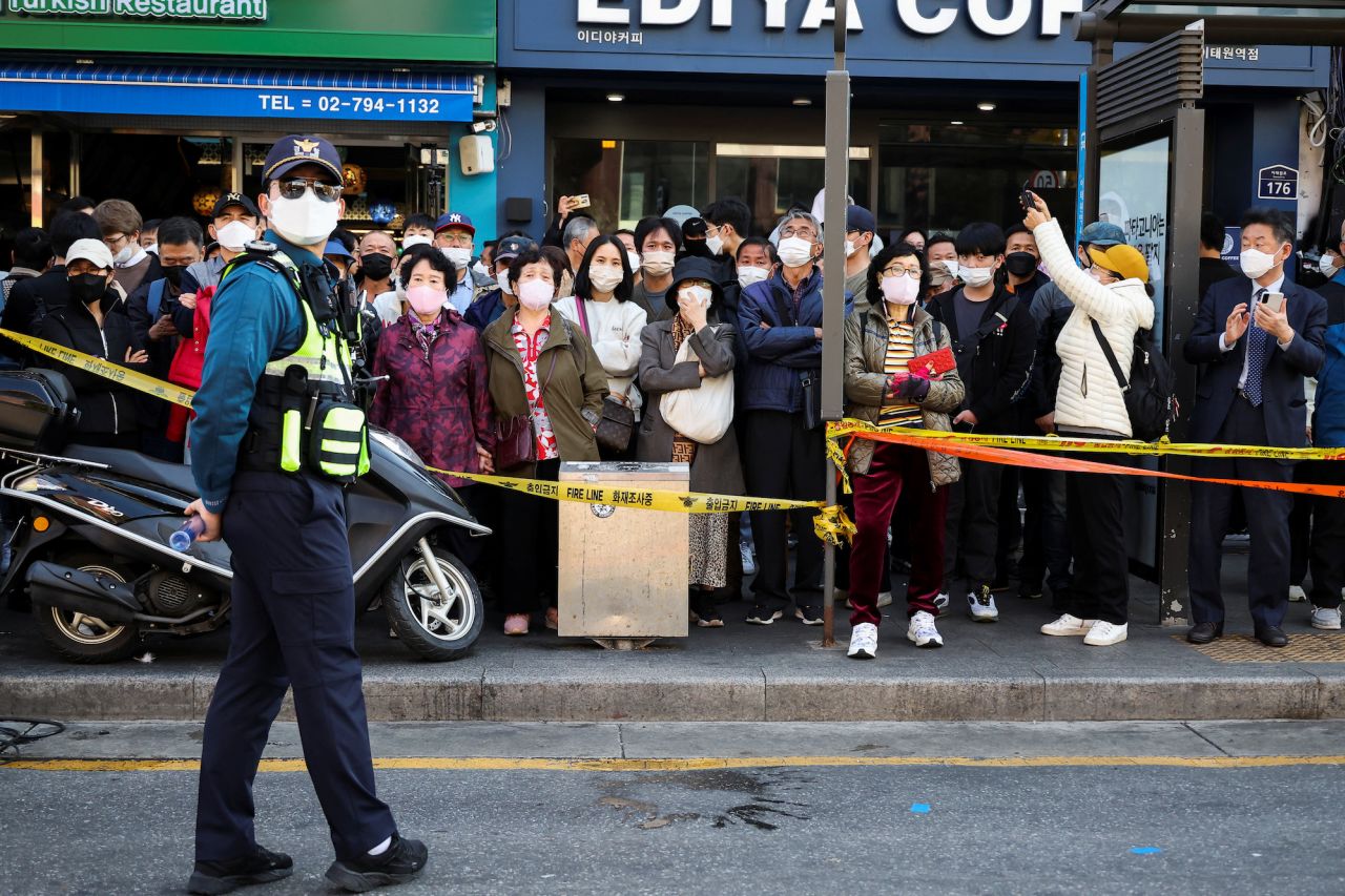 People look on as a policeman patrols the scene of the crowd surge.