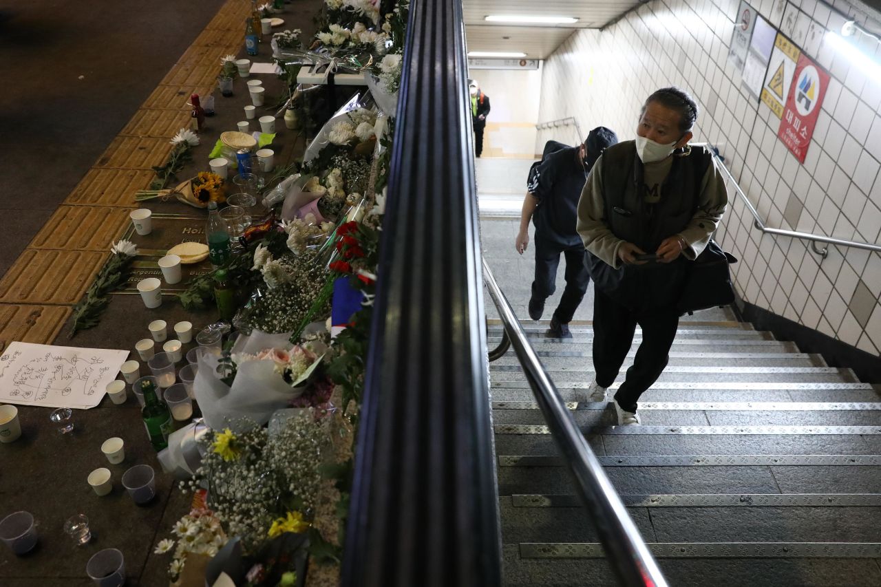 A man walks next to flowers along the street in remembrance for those who lost their lives to the crowd surge in Seoul.