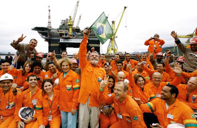 Lula waves a Brazilian flag while posing for a picture in 2008 with workers of the Brasil-Fels shipyard, who built the Petrobras oil platform in Angra dos Reis, Brazil.
