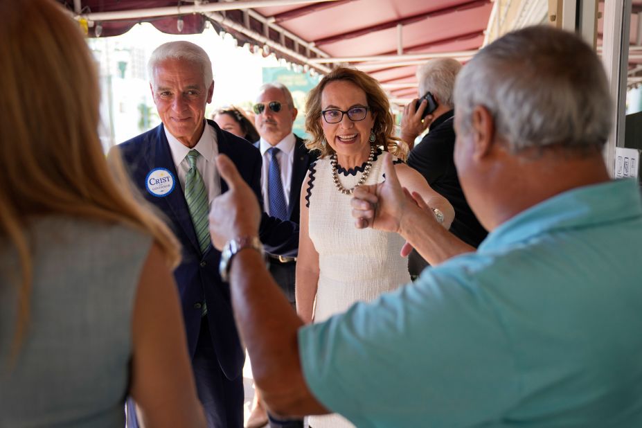 Giffords is joined by Florida gubernatorial candidate Charlie Crist, left, as they arrive at a restaurant in Miami in September 2022. State Democratic officials joined Giffords as she continued a bus tour against gun violence. 