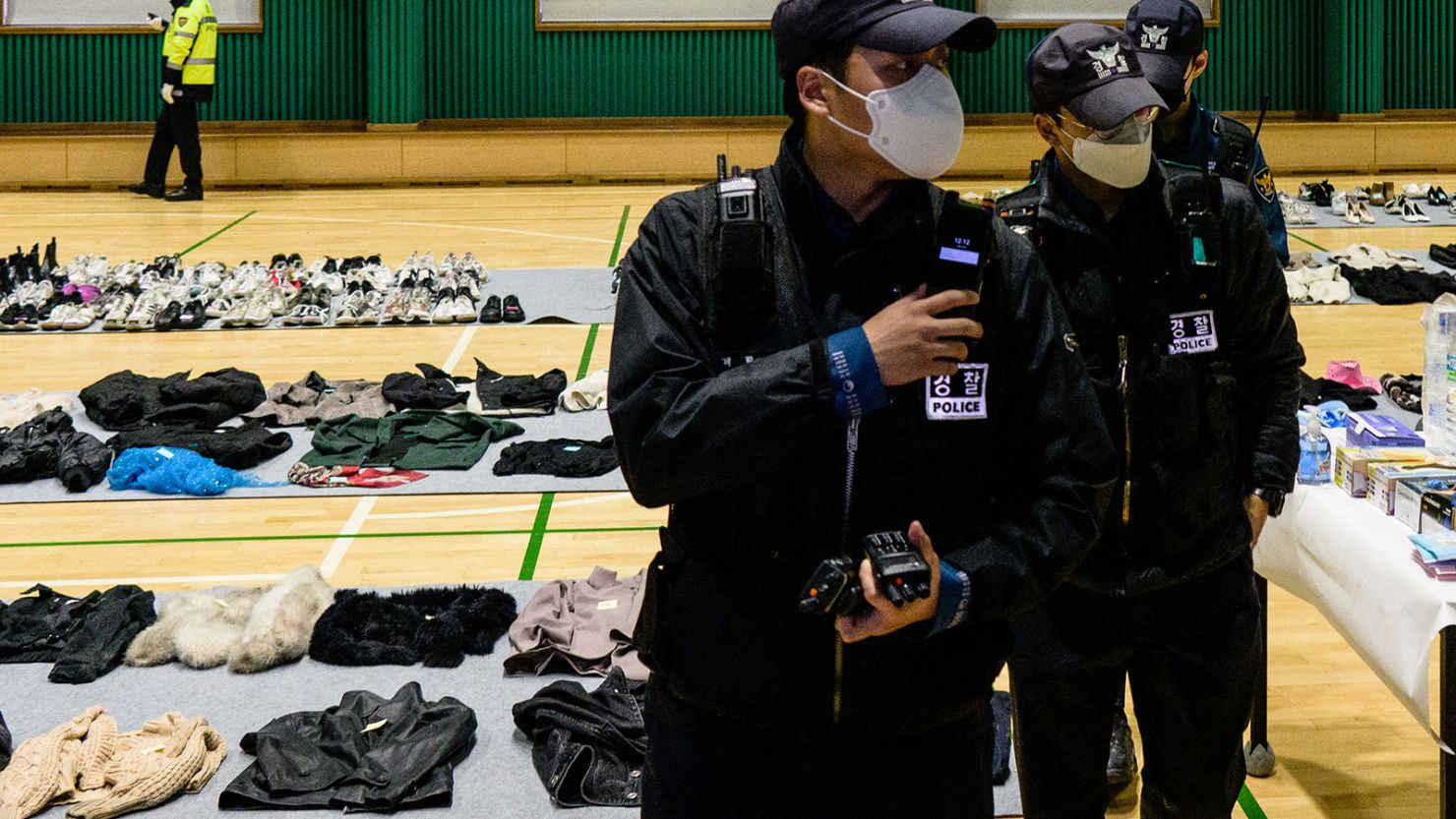 Police walk amongst personal belongings retrieved from the scene of a fatal Halloween crowd surge that killed more than 150 people in the Itaewon district after they were displayed at a gymnasium for relatives of victims to collect, in Seoul on November 1, 2022.