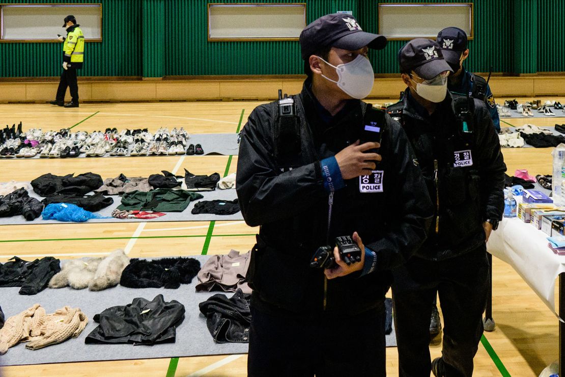 Police walk among personal belongings retrieved from the scene of a fatal Halloween crowd surge.