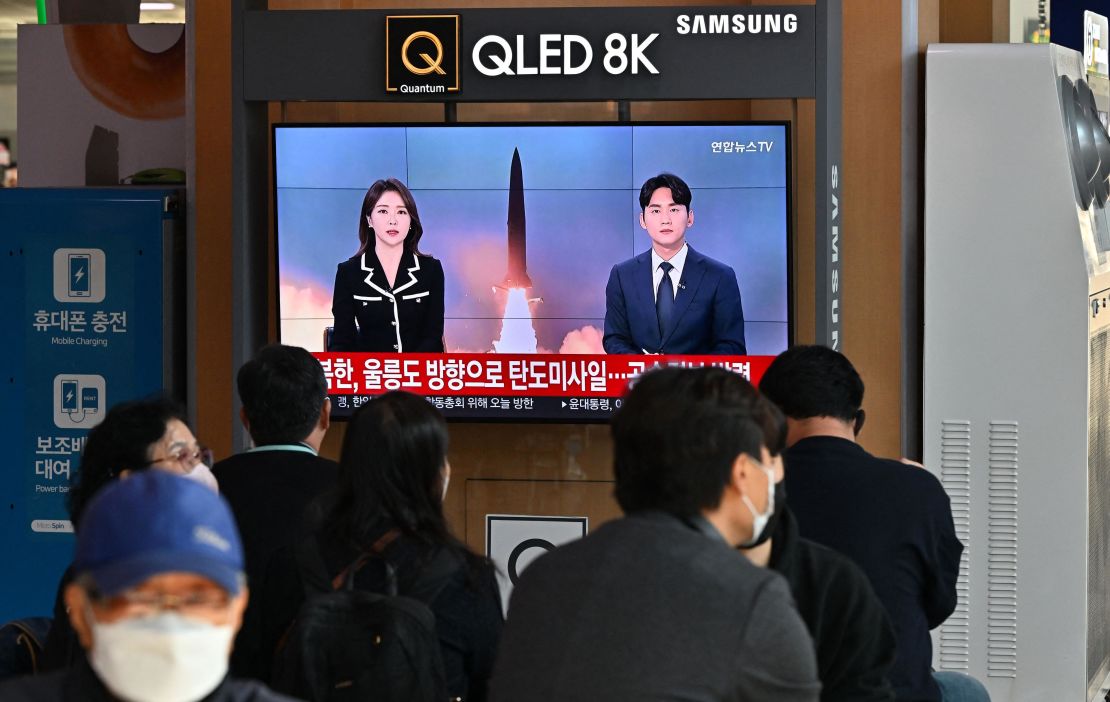 People watch a television screen showing a news broadcast with file footage of a North Korean missile test, at a railway station in Seoul on November 2, 2022.