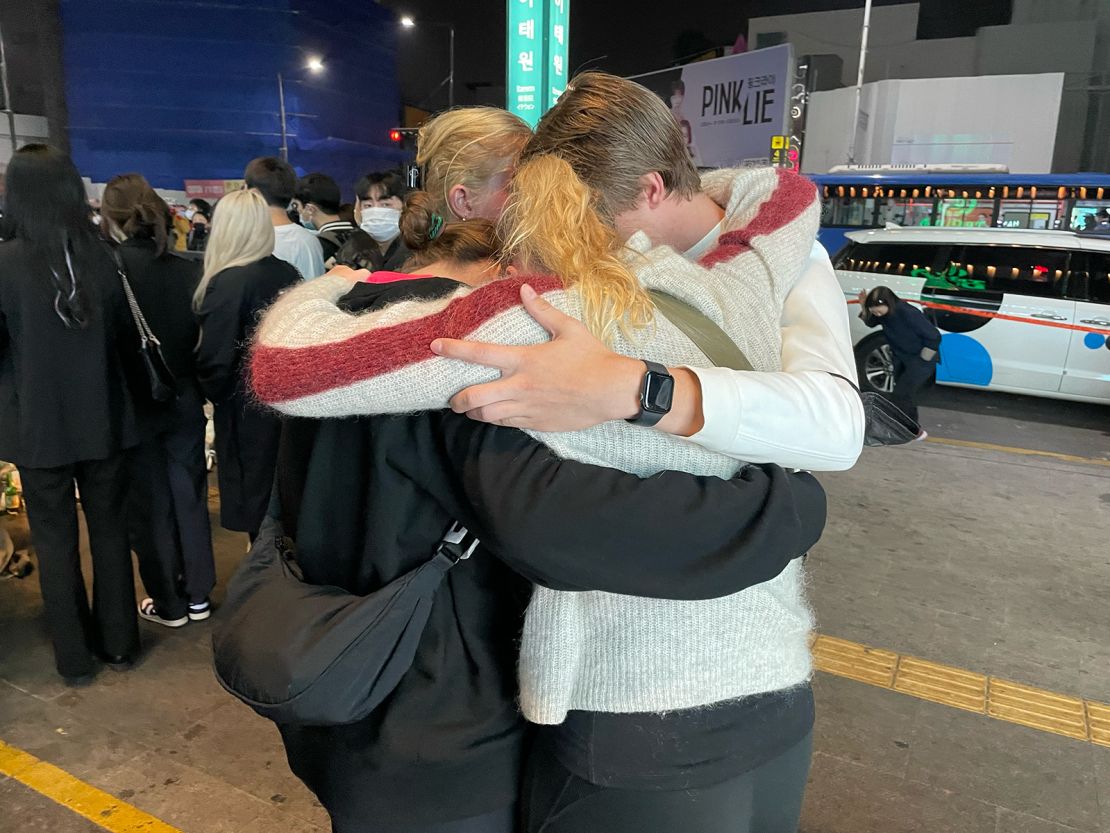 A group of Steven Blesi's friends hug next to the vigil at the Itaewon disaster site, Seoul.