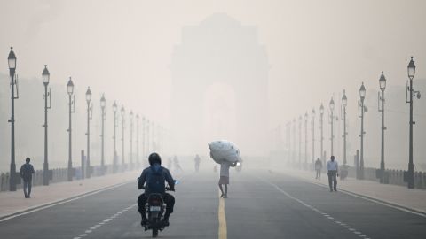 A man carries a sack along the road in front of India Gate amid smoggy conditions in New Delhi on November 1, 2022. 