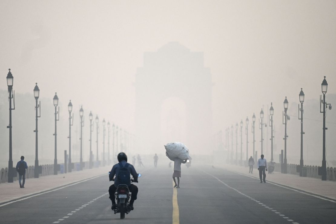 A man carries a sack along the road in front of India Gate amid smoggy conditions in New Delhi on November 1, 2022. 