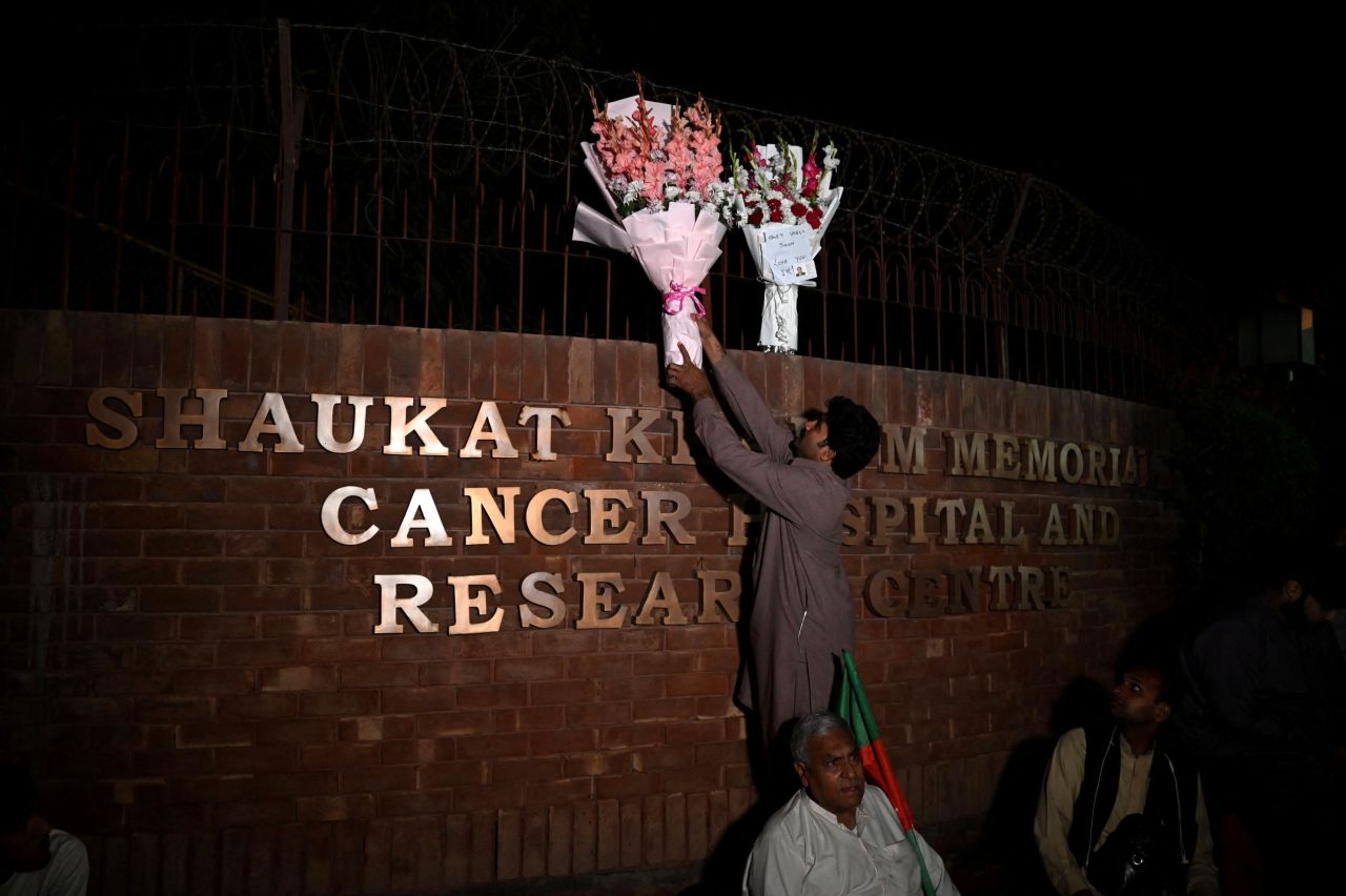 A person places flowers outside the hospital where Pakistan's former Prime Minister Imran Khan is admitted after <a rel=