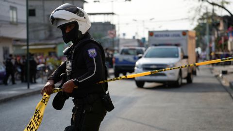 A police officer puts up tape at a crime scene where colleagues were killed in response to prisoner transfers from overcrowded prisons.