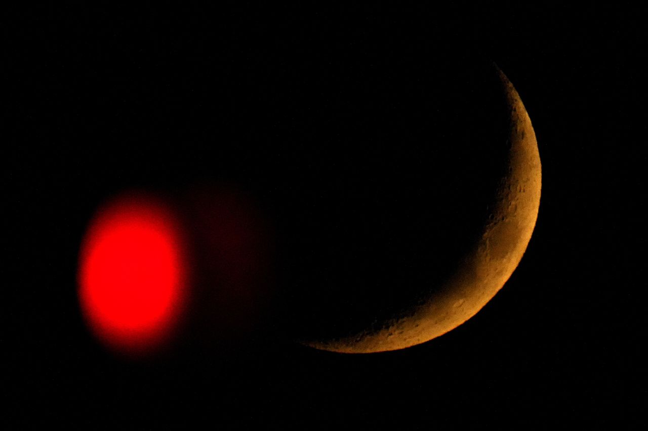 The crescent moon sets behind a stop light in Overland Park, Kansas, on Friday, October, 28.