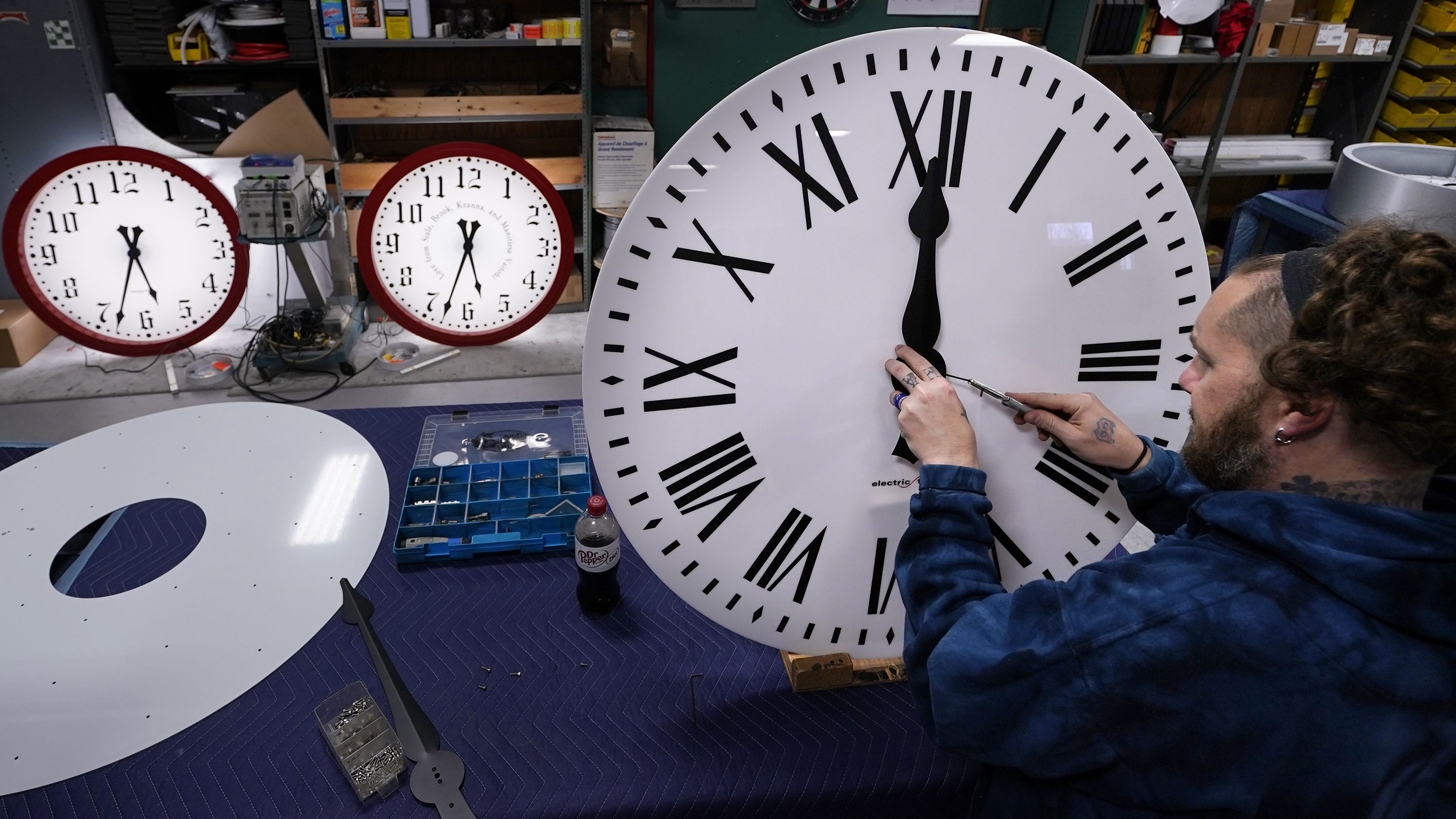 Ian Roders fastens the hands to a clock at the Electric Time Company in Medfield, Massachusetts, on Tuesday, November 1. Daylight saving time ends at 2 a.m. on Sunday, November 6, when clocks in the US are set back one hour.