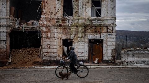 A woman cycles past a damaged building in the city of Kupiansk, Kharkiv region, November 3, 2022, during the Russian invasion of Ukraine.