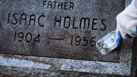 A Friends of Lebanon volunteer removes mildew from a headstone during a recent cleanup day.