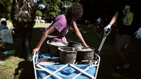 Renee Crankfield, who has generations of her family buried in the cemetery, helps carry drainage gravel.