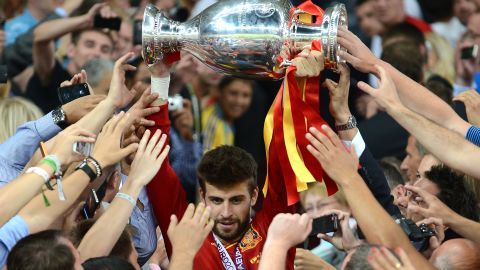 Pique carries the UEFA European Championship trophy on the steps after the game as he is mobbed by fans. 