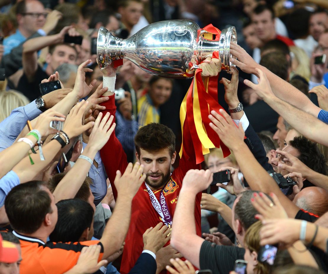 Piqué carries the UEFA European Championship trophy down the steps after the game, as he is mobbed by fans. 