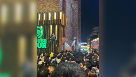 Seorang pria terlihat memanjat gedung untuk melarikan diri dari kerumunan di bawah di Itaewon, Seoul, pada 29 Oktober. 