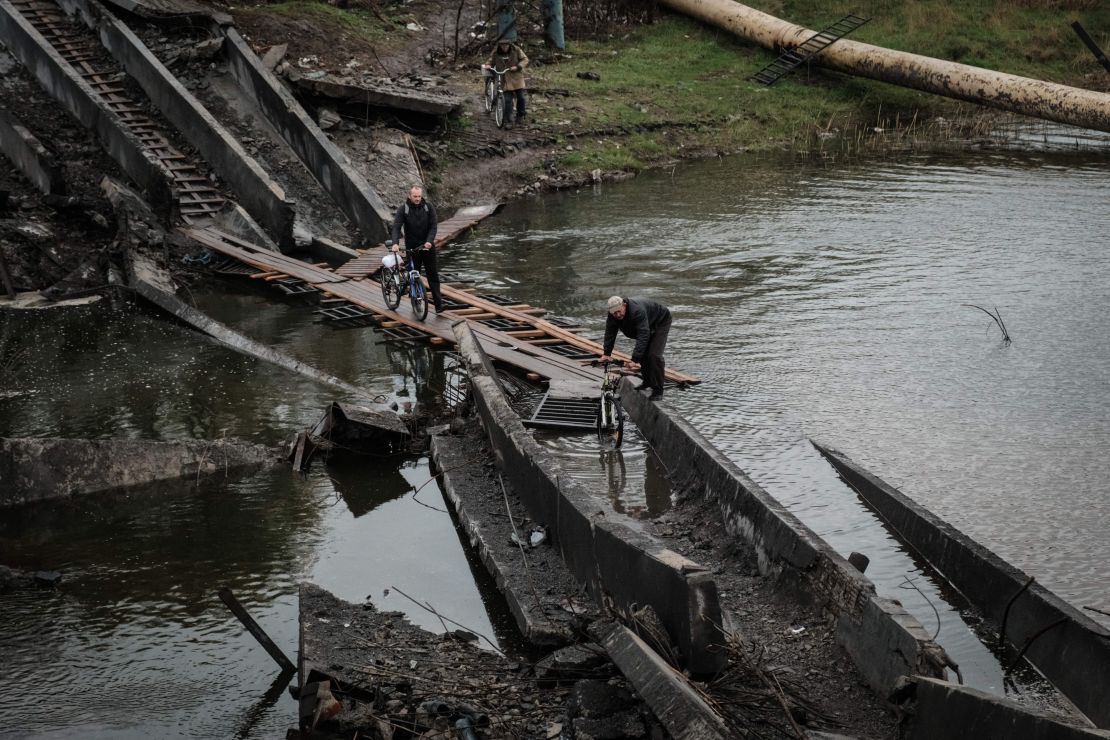 Men cross the destroyed bridge with their bicycles in the frontline town of Bakhmut in the Donetsk region on October 11, 2022