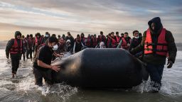 TOPSHOT - Migrants move a smuggling boat into the water as they embark on the beach of Gravelines, near Dunkirk, northern France on October 12, 2022, in an attempt to cross the English Channel. - Since the beginning of the year, more than 33,500 people have already made the perilous crossing of the English Channel, one of the busiest shipping lanes in the world, where more than 400 commercial ships pass each day. (Photo by Sameer Al-DOUMY / AFP) (Photo by SAMEER AL-DOUMY/AFP via Getty Images)
