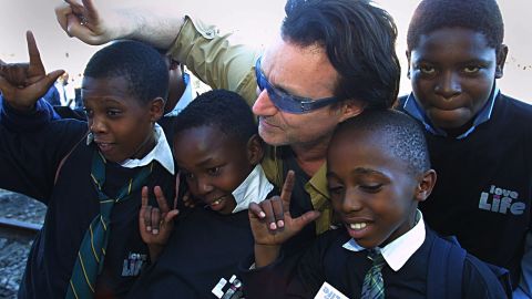 Irish rocker Bono, lead singer of U2, poses with schoolchildren in the Soweto township outside Johannesburg, South Africa, in May 2002.