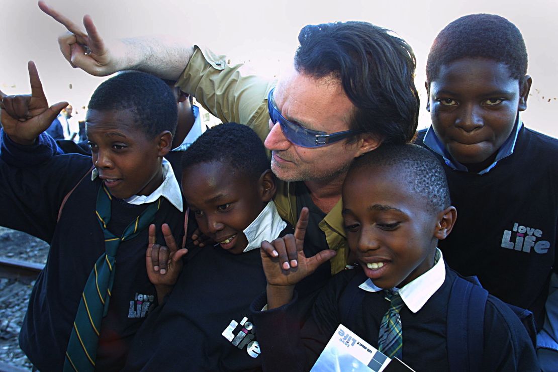 Irish rocker Bono, lead singer of U2, poses with schoolchildren  in the Soweto township outside Johannesburg, South Africa, in May 2002. 