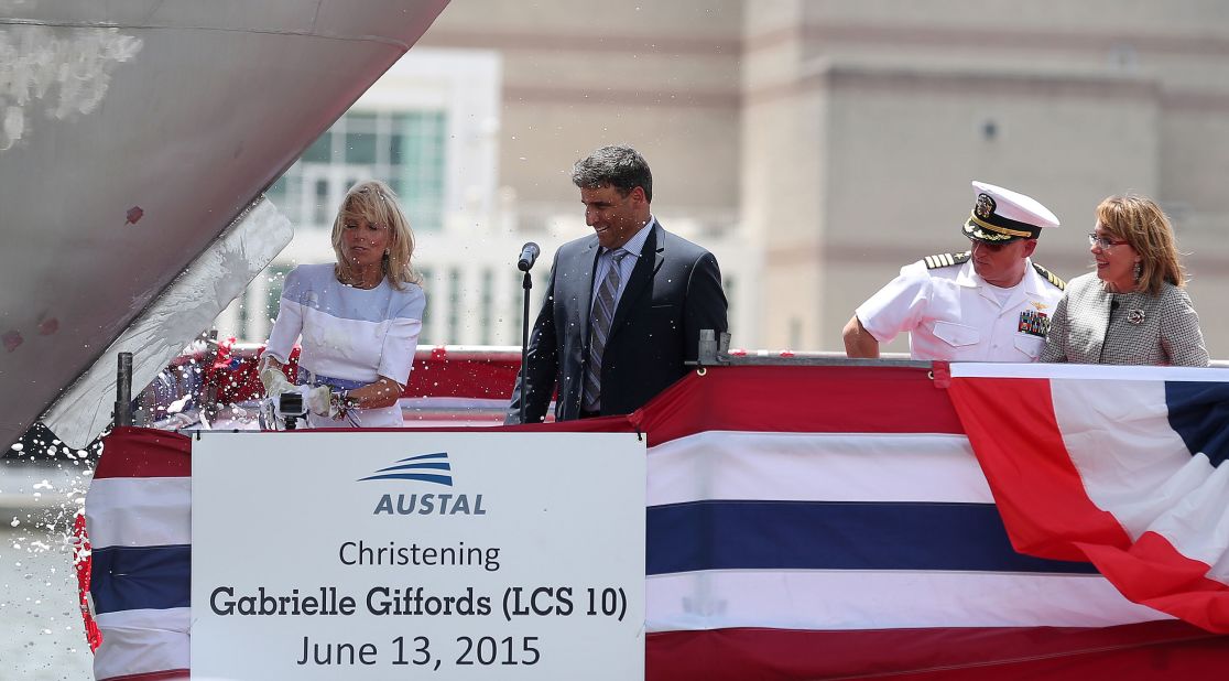 Jill Biden, wife of Biden, smashes a champagne bottle on the bow of a US Navy vessel that was being named in Giffords' honor in June 2015. Giffords and Kelly are on the right.