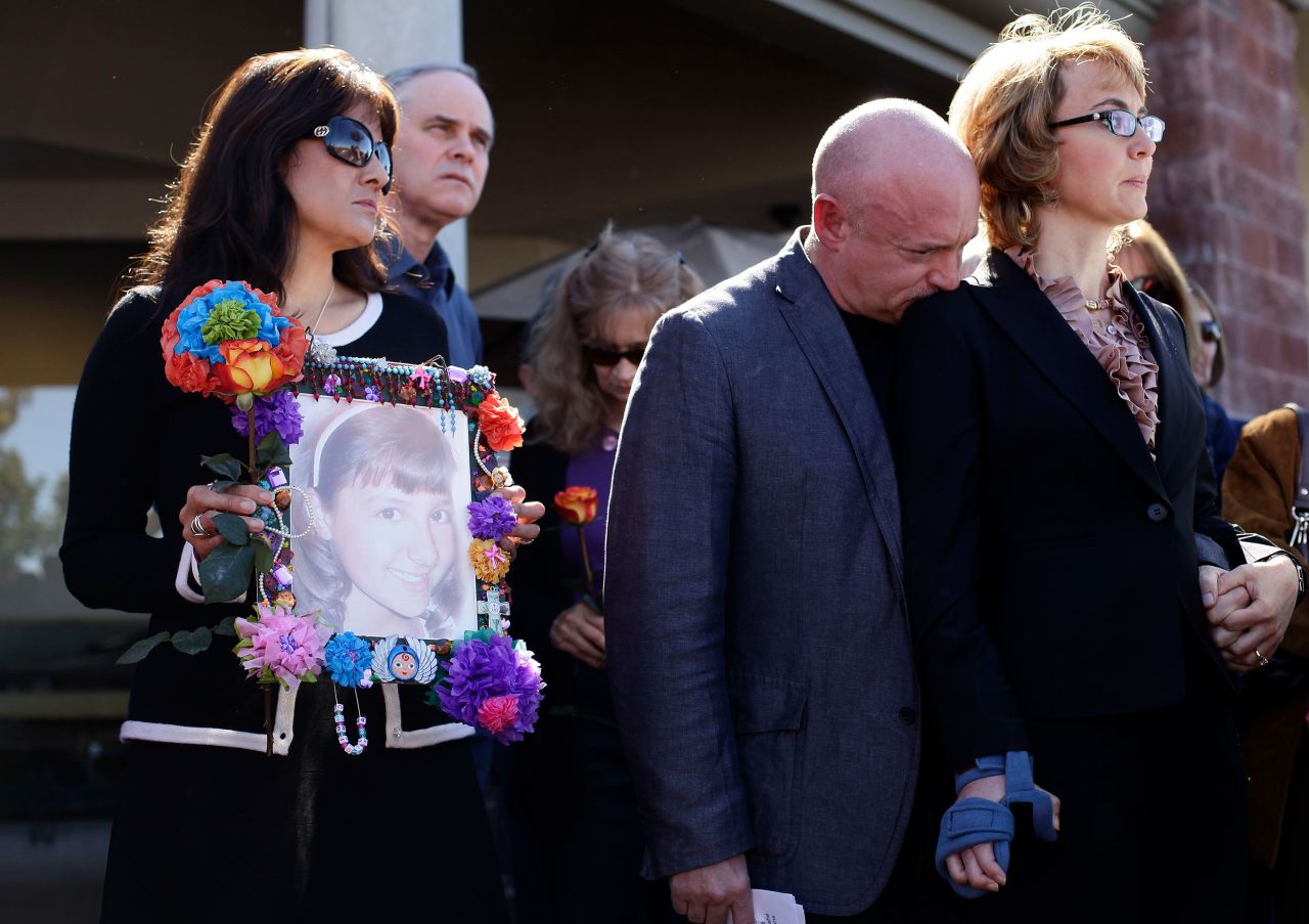 Giffords and Kelly attend a March 2013 news conference in Tucson that urged Congress to provide stricter gun control in the United States. At left, Roxanna Green holds a photo of her daughter, Christina Taylor Green, who was killed in the 2011 shooting.