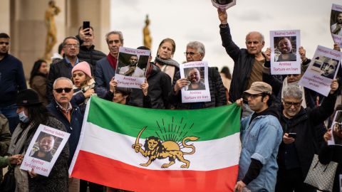 Demonstrators hold an Iranian flag and a banner with a portrait of Toomai Salehi in Paris on November 5, 2022. 
