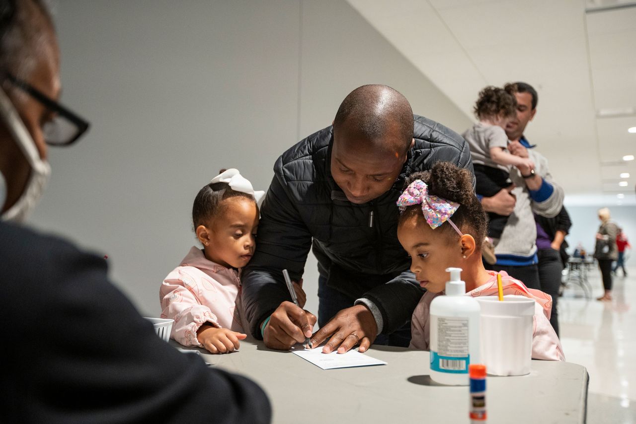 Milwaukee Mayor Cavalier Johnson signs his ballot envelope with his twin daughters on Saturday.