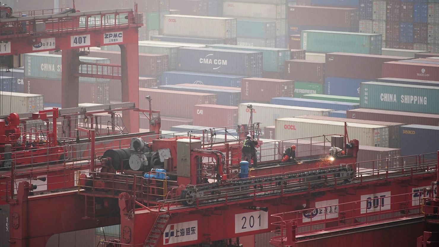 Workers are seen on a crane above containers at the Yangshan Deep Water Port in Shanghai, China January 13, 2022. 