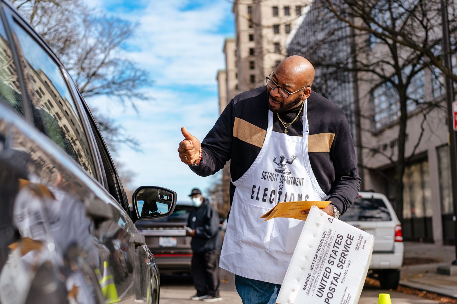 An election worker collects an absentee ballot from a car in Detroit on November 6.