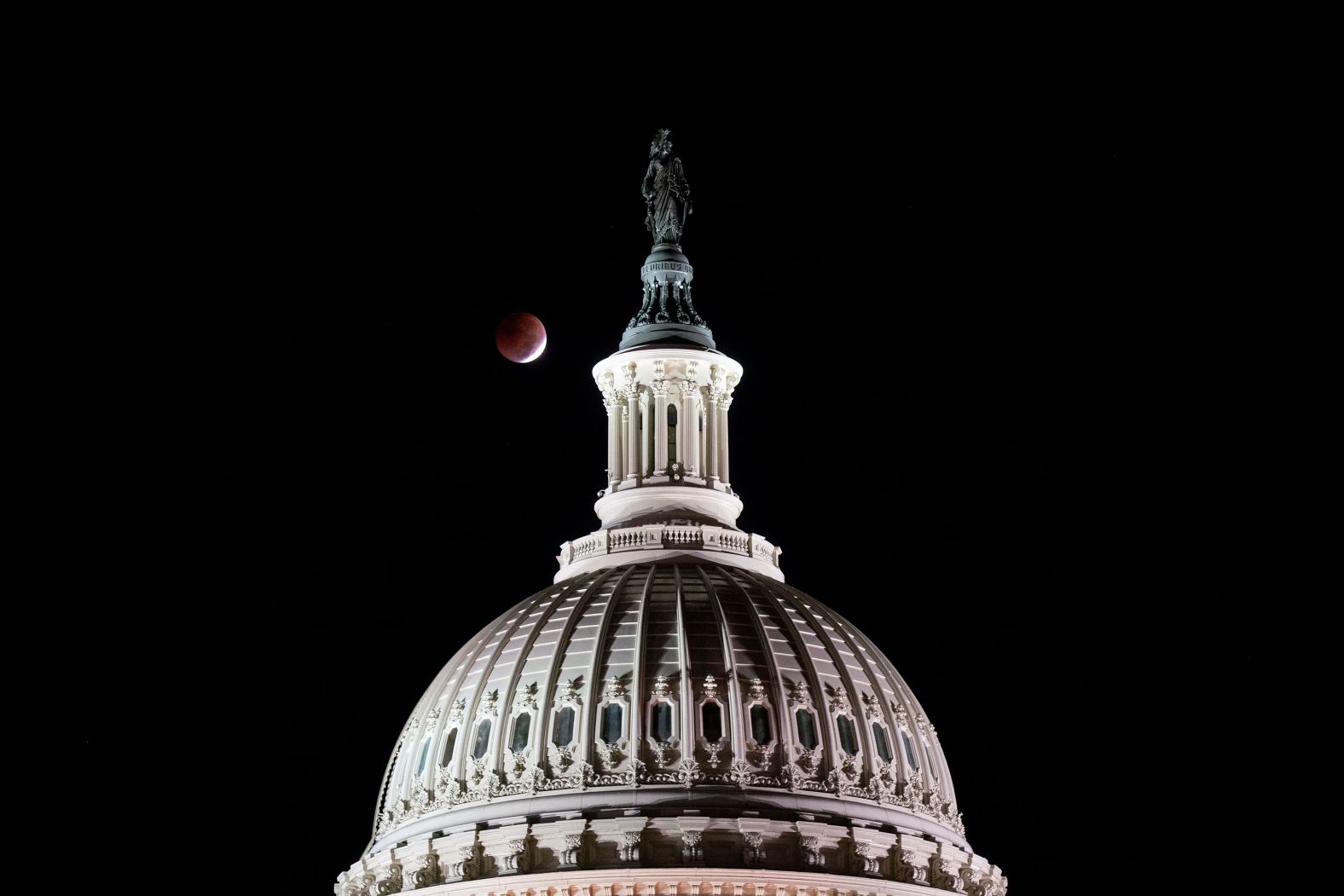 The full moon sets during a total lunar eclipse, behind the Statue of Freedom atop the Capitol dome, on the morning of the US midterm election, in Washington, DC, on November 8.