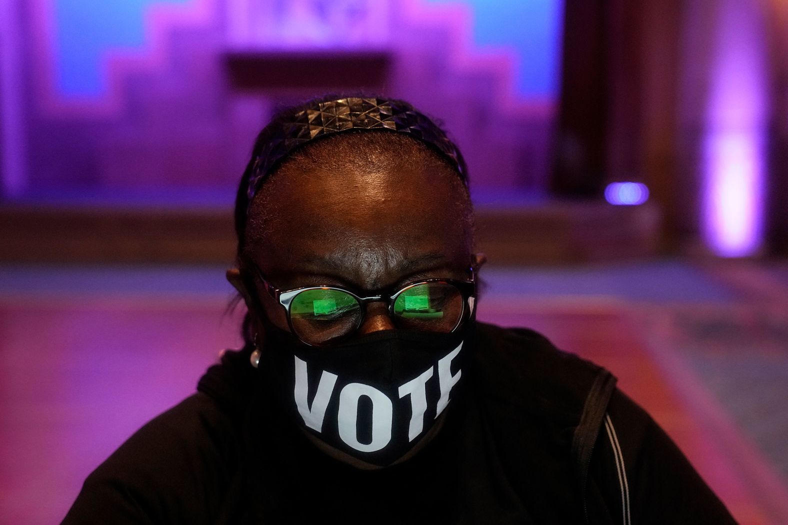 A poll worker in Atlanta wears a "vote" mask while checking in voters on Election Day.