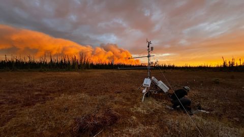 Fumaça de um incêndio florestal é visível atrás de uma torre de monitoramento de permafrost na Estação de Pesquisa Scotty Creek, nos Territórios do Noroeste do Canadá, em setembro.  A torre foi incendiada em outubro devido a uma atividade incomum de incêndios florestais.
