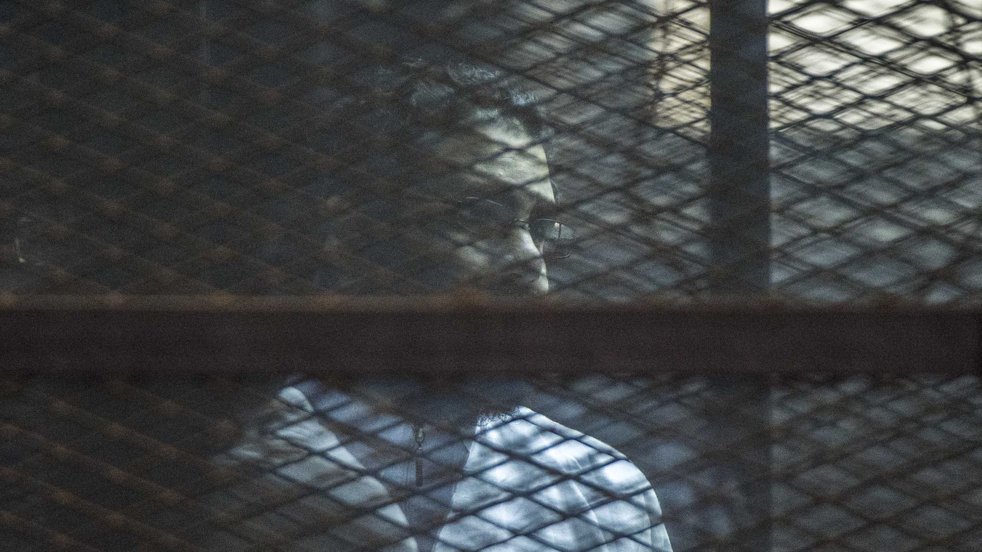 Prominent British-Egyptian activist Alaa Abd el-Fattah stands in a cage during a verdict hearing for 21 people over an unauthorized street protest in 2013, in a courtroom in Cairo, Egypt in 2015.