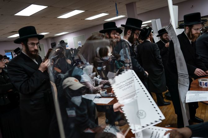 Poll workers are reflected by a piece of glass as people collect their ballot papers in Brooklyn, New York.