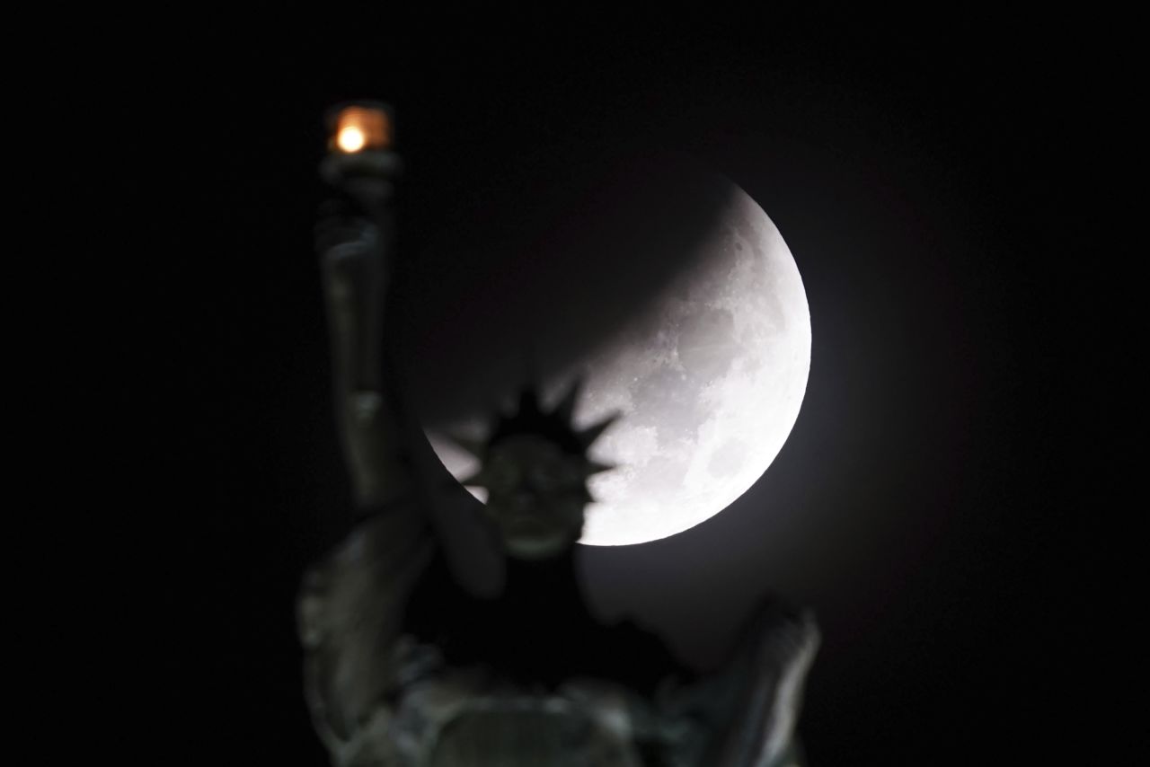 The Earth's shadow passes in front of the moon during the lunar eclipse, as Lady Liberty atop the Liberty Building in Buffalo, New York, does her part to light up the early morning sky on November 8.