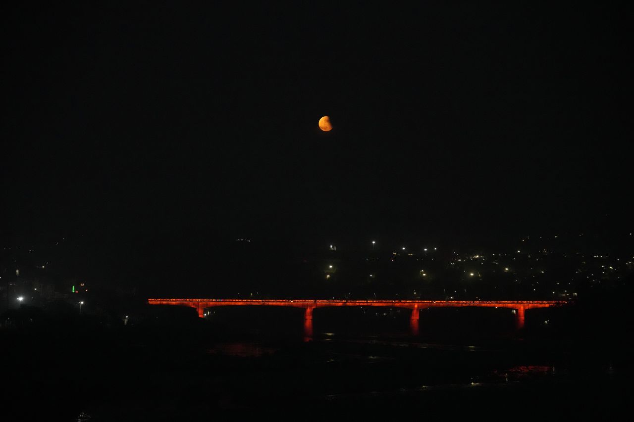 The lunar eclipse is seen over Tawi bridge in Jammu, India, on November 8.