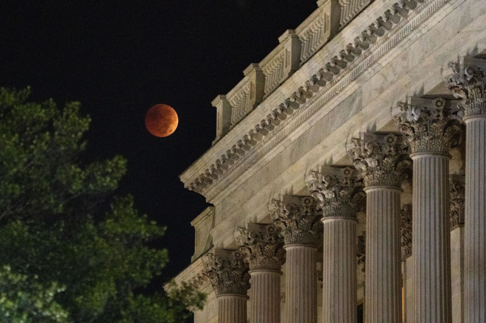 The blood moon sets behind the US Capitol on November 8, in Washington, DC. In a total lunar eclipse, the Earth's atmosphere disperses sunlight, causing the moon's rusty red appearance.