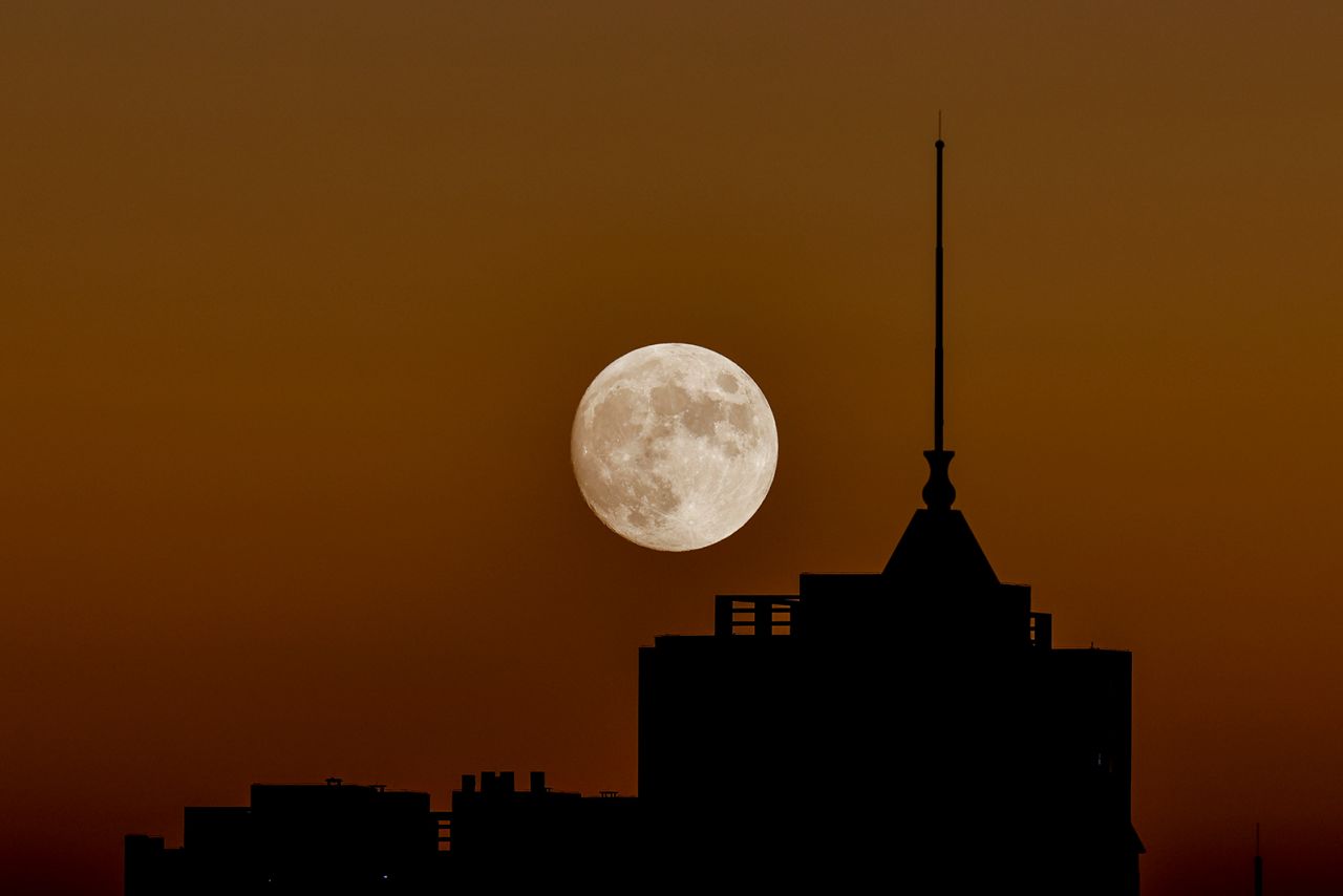 This month's full moon, known as the beaver moon, rises over buildings during a light show in Beijing on November 7.